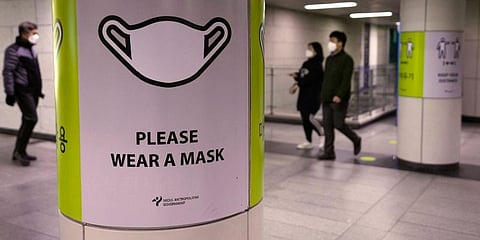People wearing face masks pass by posters reminding precautions against the coronavirus at a subway station in Seoul, South Korea. (Photo | AP)
