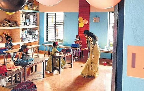 A teacher talks to a student at the Government UP School at Perambra in Kozhikode on Monday. Adhering to Covid protocol, children were seated separately after schools reopened in the state on Monday