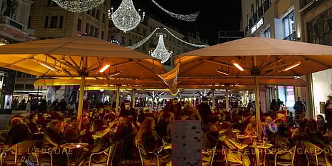 People sit at an outdoor cafe on a street decorated with Christmas lights in Vienna, Austria. (Photo | AP)