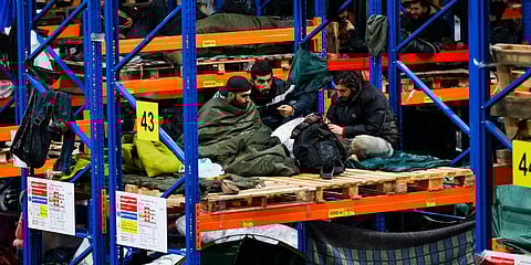 Migrants rest inside a logistics center at the checkpoint 'Kuznitsa' at the Belarus-Poland border near Grodno, Belarus. (Photo | AP)
