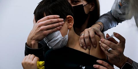Israeli child Liam Lev Tov, 6, in the arms of his mother, receives a Pfizer-BioNTech COVID-19 vaccine from medical staff at Clalit Health services in Tel Aviv, Israel. (Photo | AP)
