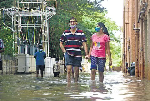 Residents make their way through a driveway flooded in ankle-deep water after heavy rain, at Kendriya Vihar in Bengaluru on Tuesday | ashishkrishna hp