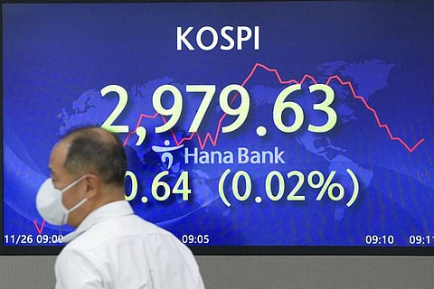 A currency trader walks by the screens showing the Korea Composite Stock Price Index (KOSPI) at a foreign exchange dealing room in Seoul (Photo | AP)