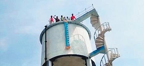 Ryots stage a protest after climbing atop a water tank at Indurthi in Chigurumamidi mandal, Karimnagar district, on Thursday, Nov 25, 2021, seeking the purchase of their paddy.