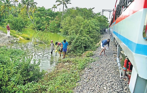Youngsters wading through stagnated water to reach the railway tracks and cross over to the other side. There are no other transportation facilities for the residents