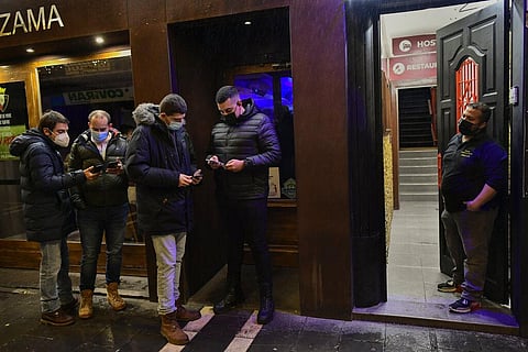 A doorman controls European passport COVID-19 to customers before the access of a bar discotheque, in Pamplona, northern Spain. Saturday, Nov. 27, 2021. (Photo | AP)