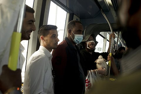 A man who opposes coronavirus vaccine mandates wears a mask altered to make a statement, while carrying a toy sheep and an outsized syringe as he rides a crowded train in Jerusalem. (Photo | AP)