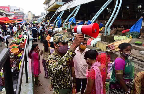 A BBMP marshal creates awareness among shoppers on the need to follow  Covid-appropriate behaviour near KR Market. (Photo| Shriram BN, EPS)