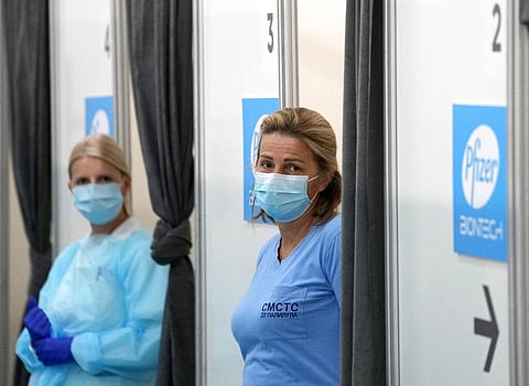 Medical workers wearing protective gear wait to administer the COVID-19 vaccine (Photo | AP)
