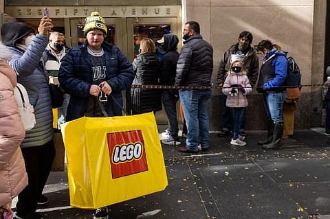 A man carrying a shopping bag walks out of a LEGO store in New York City, New York on Black Friday, November 26, 2021. (Photo | AFP)