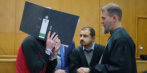 With a file folder in front of his face, the Iraqi Taha Al-J. (L) talks to his lawyers Serkan Alkan (C) and Martin Heising before the sentencing in the Frankfurt Higher Regional Court. (Photo | AP)