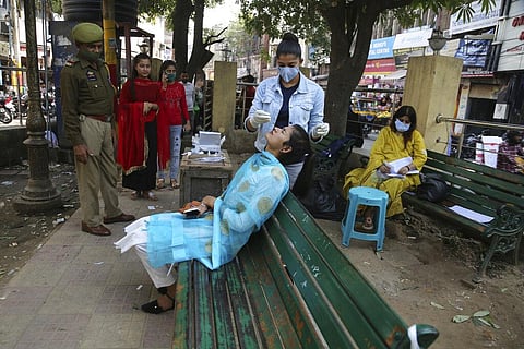 A health worker takes a nasal swab sample of a woman to test for COVID-19 in Jammu. (Photo | AP)
