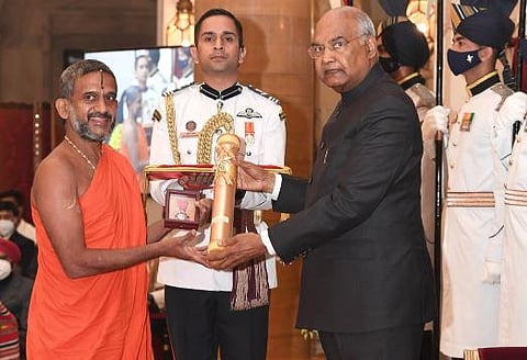 Sri Vishwaprasanna Theertha Swamiji of Sri Pejavar Matha receives the award on behalf of his senior Sri Vishwesha Theertha Swamiji. (Photo | EPS)