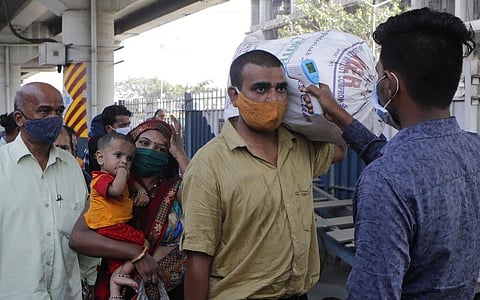 A health worker checks the body temperature of a passengers at a railway station as a precaution aganist coronavirus before allowing them to enter into the city, in Mumbai. (Photo | AP)
