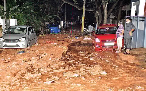 Residents standing on the mud-filled road after a 70cm pipeline burst at  Kanaka Nagar on Thursday, Dec 9, 2021 evening. (Photo | Express)