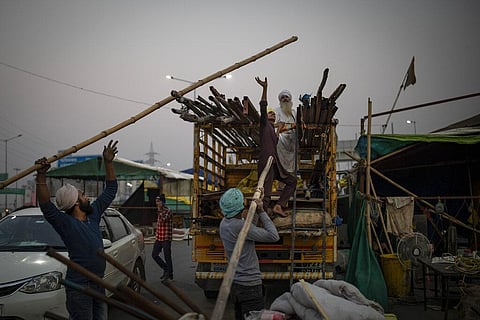 Indian farmers load bamboo and iron rods onto a truck as they dismantle temporary structures used during protests in Ghazipur, outskirts of New Delhi. (Photo | AP)