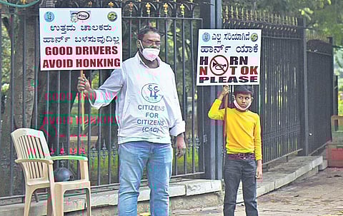 A Citizens For Citizens member and a boy hold placards against honking in Cubbon Park on Monday. (Photo | Vinod Kumar T/EPS)