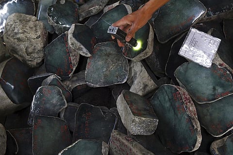 A merchant examines a jade stone displayed at the Gems Emporium in Naypyitaw, Myanmar (Photo | AP)