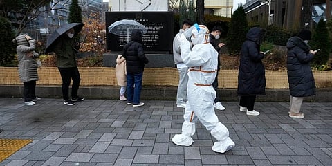 A medical worker passes by people as they wait for the coronavirus testing outside a public health center in Seoul, South Korea. (Photo | AP)