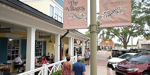 People sit in an outdoor dining area of a restaurant in the Lake Sumter Landing Market Square in The Villages, Fla. (Photo | AP)