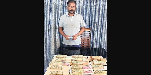 KSPCB engineer Harees AM with the unaccounted money recovered from his flat in Aluva on Thursday. (Photo | EPS)