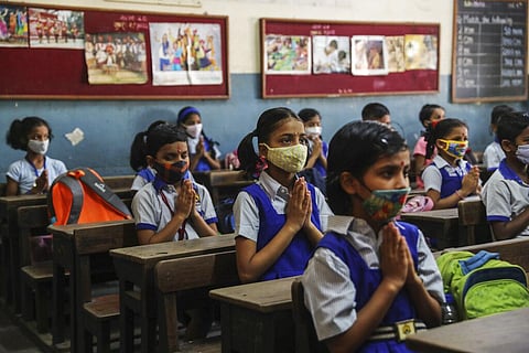 Students wearing masks say a prayer as they prepare to attend classes at a school in Mumbai, India, Wednesday, Dec.15, 2021. (Photo | AP)