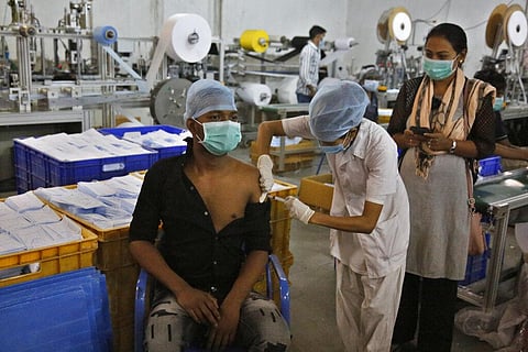 An Indian health worker administers the Covishield vaccine for COVID-19 to a worker at the factory of a face mask manufacturer on the outskirts of Ahmedabad. (Photo | AP)