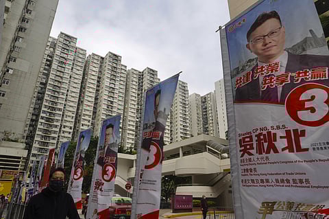 A man walks past the flags of pro-Beijing candidate Ng Chau-pei at a street in Hong Kong Sunday, Dec. 19, 2021. (Photo | AP)