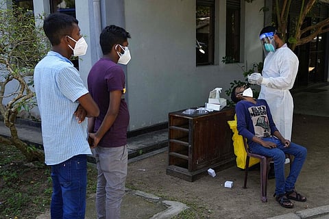 A Sri Lankan health worker collects a swab sample of a man to test for COVID-19 as others wait for their turn in Colombo. (Photo | AP)
