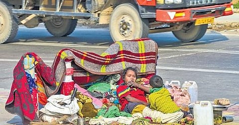 A homeless family creates a barricade from blankets on a pavement to brace the cold wave in New Delhi on Saturday | Pti