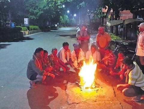 Workers keep themselves warm in front of a bonfire on a cold Saturday morning at Seethammadhara in Visakhapatnam, Dec 18, 2021. (Photo I Express, G Satyanarayana)