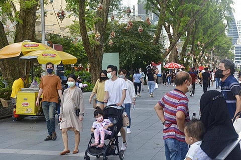 People wearing protective face masks walk along the Orchard Road shopping area in Singapore (Photo | AP)