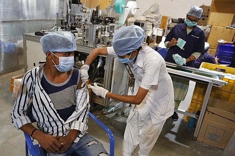 An Indian health worker administers the Covishield vaccine for COVID-19 to a worker at the factory of a face mask manufacturer on the outskirts of Ahmedabad. (Photo | AP)