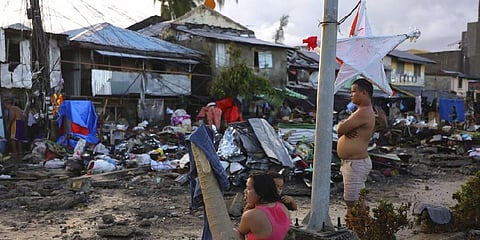 A family stands outside damaged homes due to Typhoon Rai in Surigao city, Surigao del Norte, southern Philippines (Photo | AP)