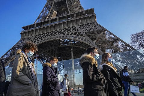 People wearing face masks to protect against COVID-19 walk past the Eiffel Tower in Paris. (Photo | AP)