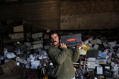 A Palestinian worker carries a discarded battery at a warehouse in Jebaliya, Gaza Strip, Wednesday, Dec. 15, 2021. (Photo | AP)
