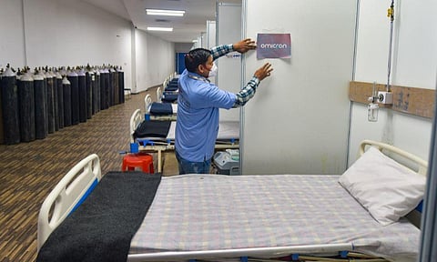 A worker pastes a sticker on a wall of a COVID-19 facility at Commonwealth Games Village in view of the rising Omicron cases in New Delhi. (Photo | PTI)