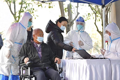 In this photo released by China's Xinhua News Agency, people register for tests at a COVID-19 testing site in Xi'an in northwestern China's Shaanxi Province. (Photo | AP)