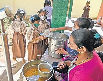 Anganwadi workers serve food to students as part of Mid-day meals at school