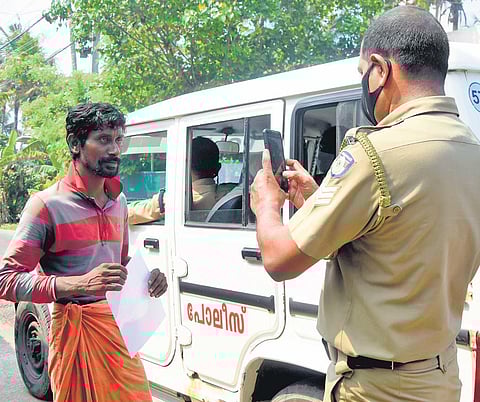 Police in Kerala take the picture of a man after handing him a fine for disregarding Covid restrictions. (File photo | EPS)