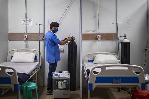 A paramedic make checks an oxygen concentrator at a makeshift COVID-19 care center at an indoor sports stadium in New Delhi. (Photo | AP)