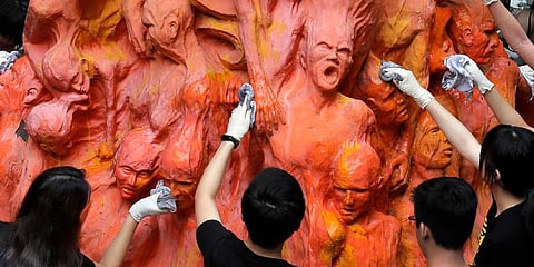 University students clean the 'Pillar of Shame' statue, a memorial for those killed in the 1989 Tiananmen crackdown, at the University of Hong Kong. (Photo | AP)