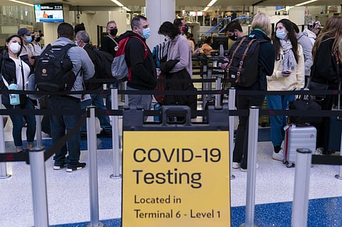 FILE - Travelers wait in line for screening near a sign for a COVID-19 testing site at the Los Angeles International Airport in Los Angeles on Nov. 24, 2021. (File photo | AP)
