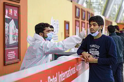 A health worker collects swab sample of a foreign traveler for COVID-19 test, at the Sardar Vallabhbhai International Airport, in Ahmedabad. (Photo | PTI)