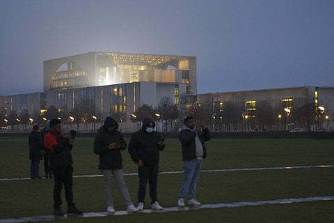 Tourists stand in front of the illuminated chancellery in Berlin, Germany, Wednesday, Dec. 29, 2021. (Photo | AP)