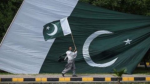 A man holds a national flag of Pakistan as he walks along a street in Islamabad.