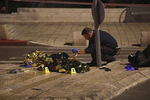An Israeli policeman examines the body of a man shot near Damascus Gate to the Old City of Jerusalem (Photo | AP)