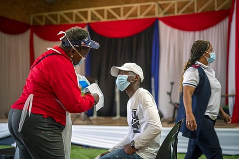 An Orange Farm, South Africa, resident listens to a nurse after receiving his jab against COVID-19 Friday Dec. 3, 2021 at the Orange Farm multipurpose center. (Photo | AP)