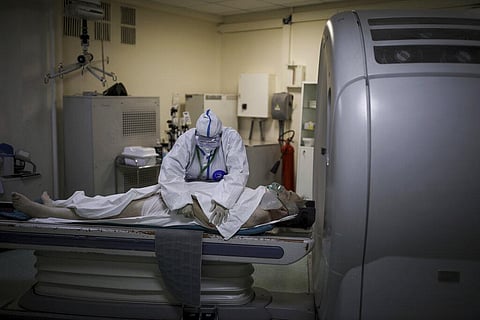 Medics wearing special suits to protect against coronavirus prepares a patient with coronavirus for computed tomography at an ICU (Photo | AP)