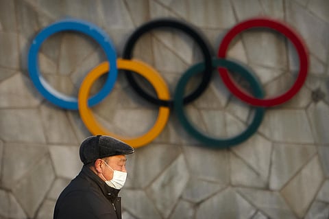 A man walks past the Olympic rings on the exterior of the National Stadium, also known as the Bird's Nest, which will be a venue for the upcoming 2022 Winter Olympics, in Beijing. (File photo | AP)